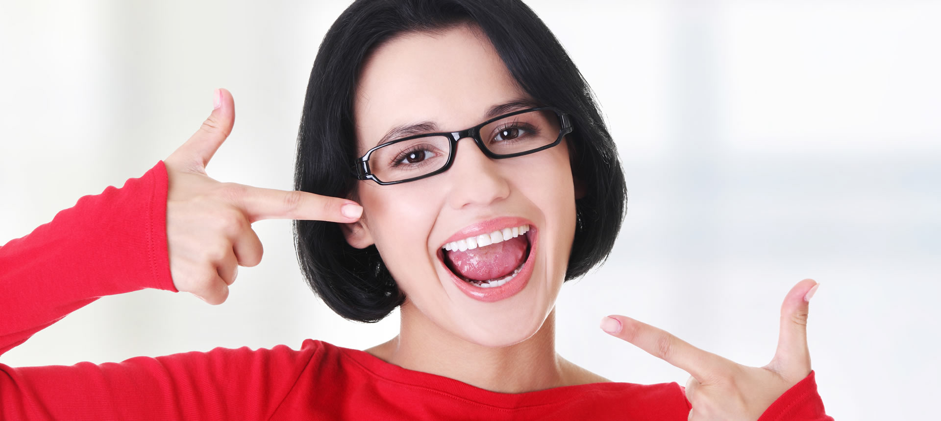 Woman with glasses in a red pullover showing her beautiful white smile