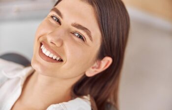 Happy young woman sitting in dental chair at dentist office