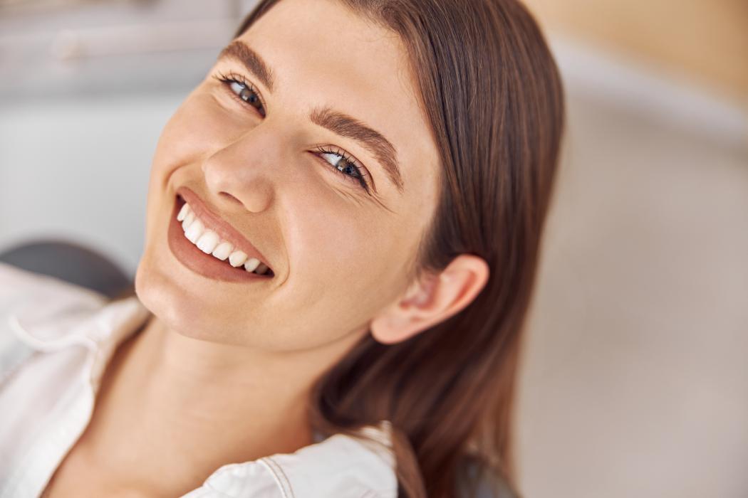 Happy young woman sitting in dental chair at dentist office