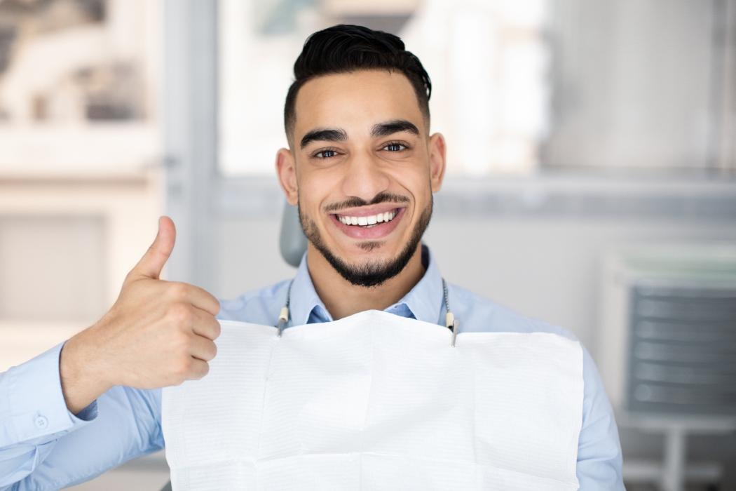 Portrait Of Happy Middle Eastern Guy Sitting In Dentist Chair And Showing Thumb Up