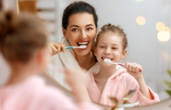 Mother and daughter child girl are brushing teeth toothbrushes in the bathroom.