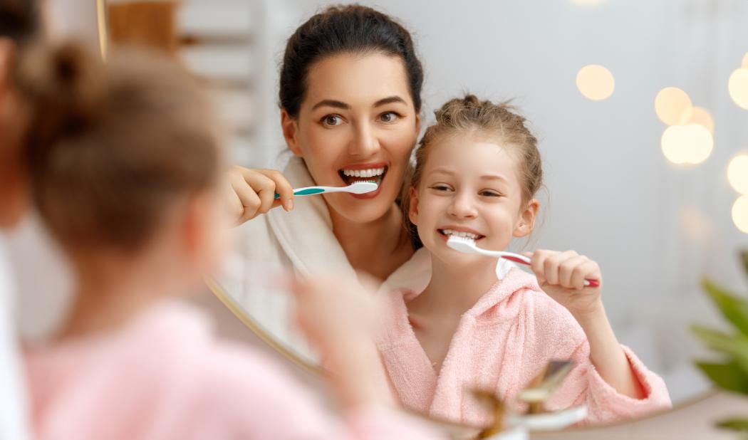 Mother and daughter child girl are brushing teeth toothbrushes in the bathroom.