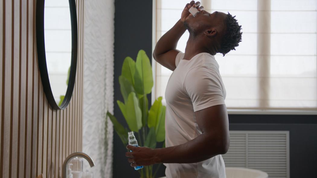 African American man rinse teeth with dental care product mouth hygiene at bathroom